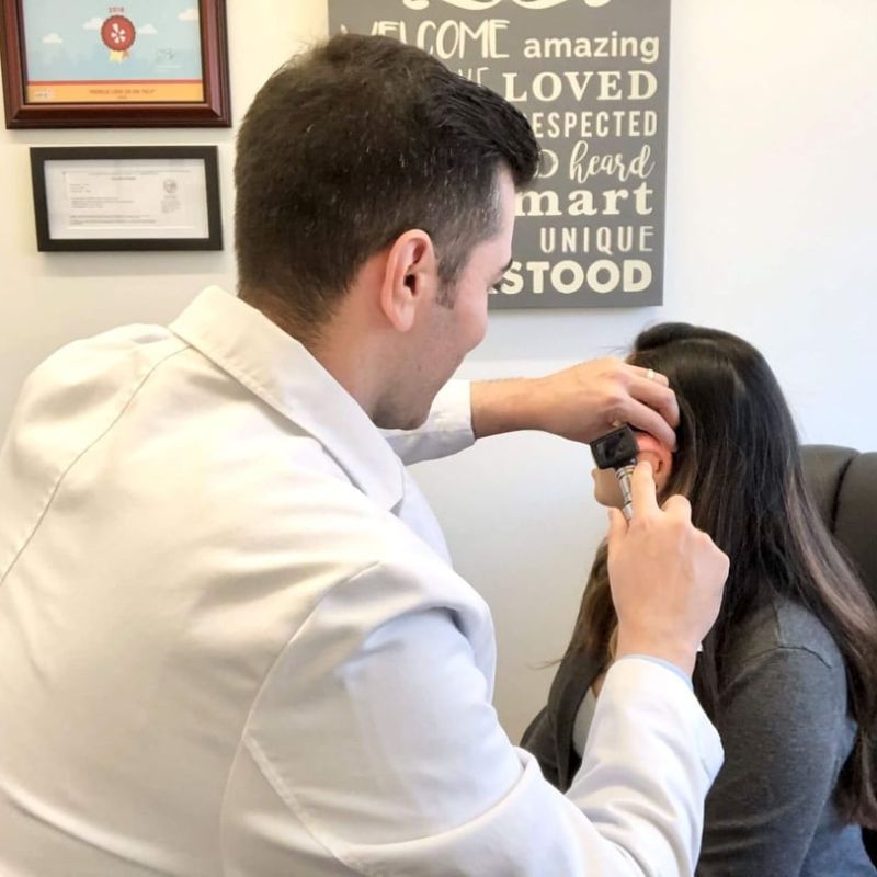 Dr. Ivory looking into a patient's ear with an otoscope